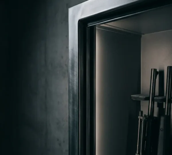 Vue d'angle d'une armoire forte ouverte montrant une collection d'armes organisée, éclairage intérieur LED tamisé